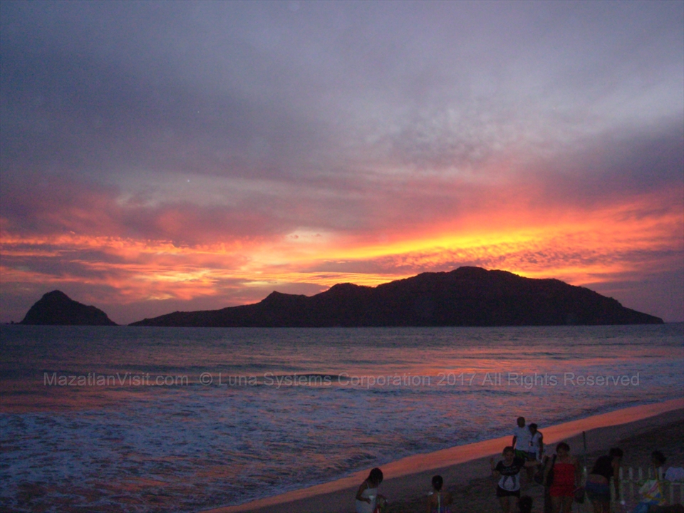 Beautiful deep orange sunset skies casting reflections across the breaking waves