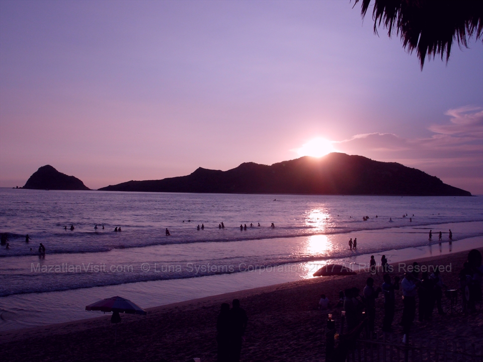 Spectacular purple and orange sunset glow reflecting over the waves in Mazatlán, Mexico