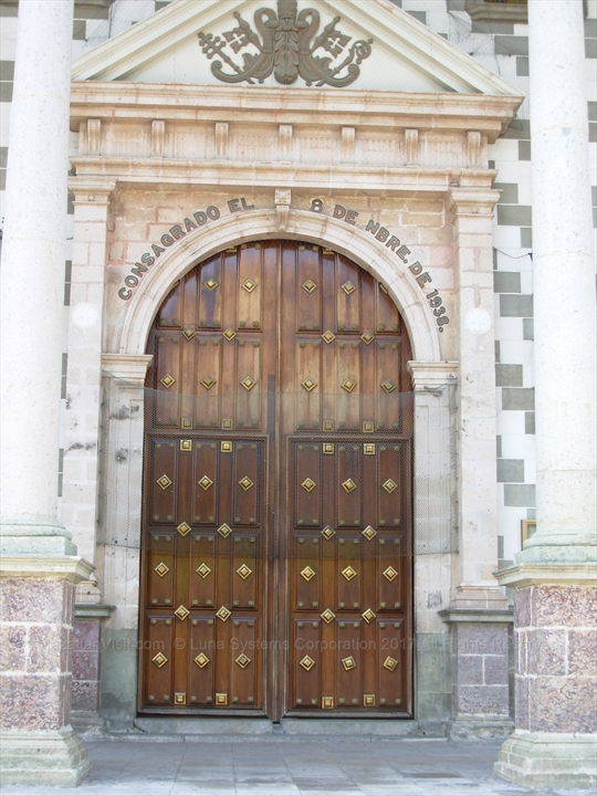 Detail view tracking the heavy carved timber entry doors of the basilica