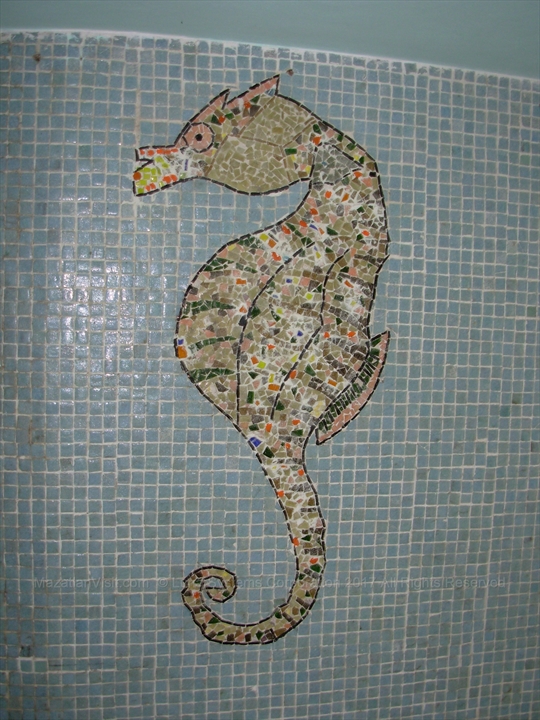 Ornate marine life tile mosaics lining the interior walls of a subterranean walkway tunnel