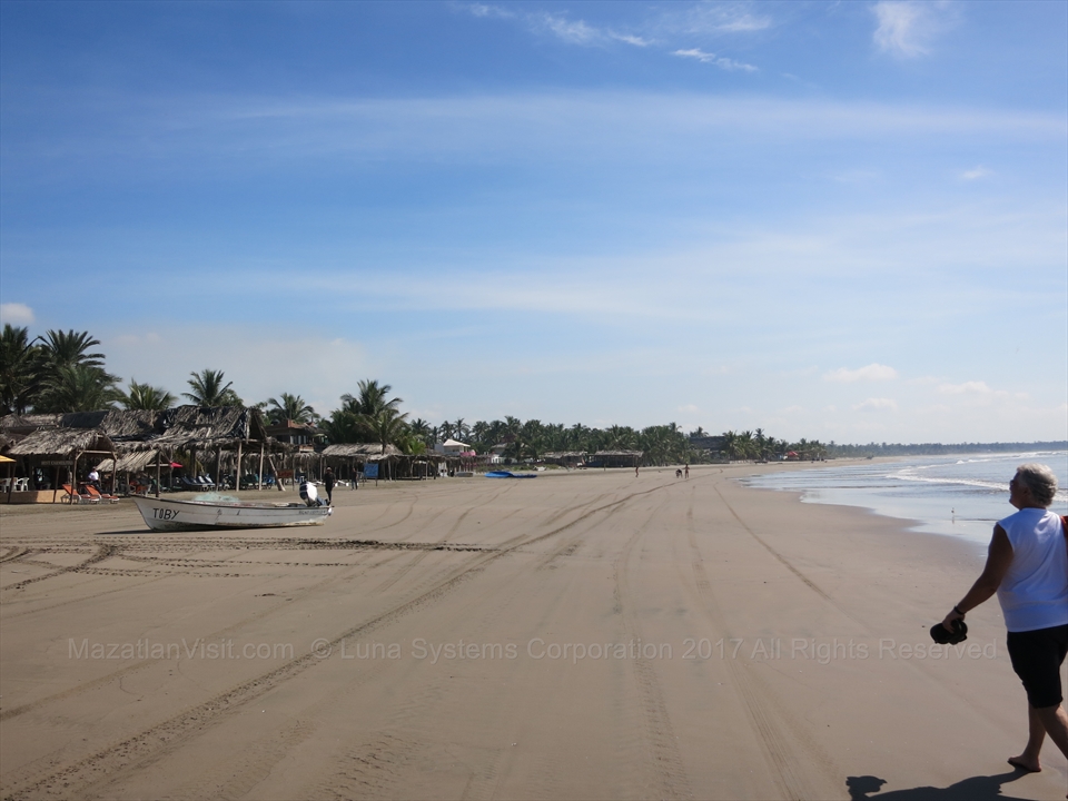 Palapa structures lining the wide flat sands of Stone Island beach