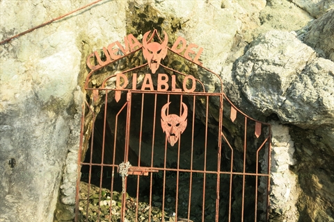 The heavy gated crimson entrance of the mysterious Devil's Cave on Paseo Claussen