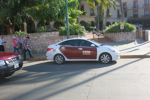 Standard red and white Nissan Eco Taxi cab operating in Mazatlán