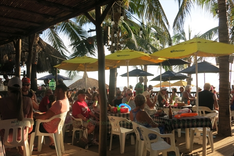Patrons enjoying cold drinks under the main beachfront palapa roof