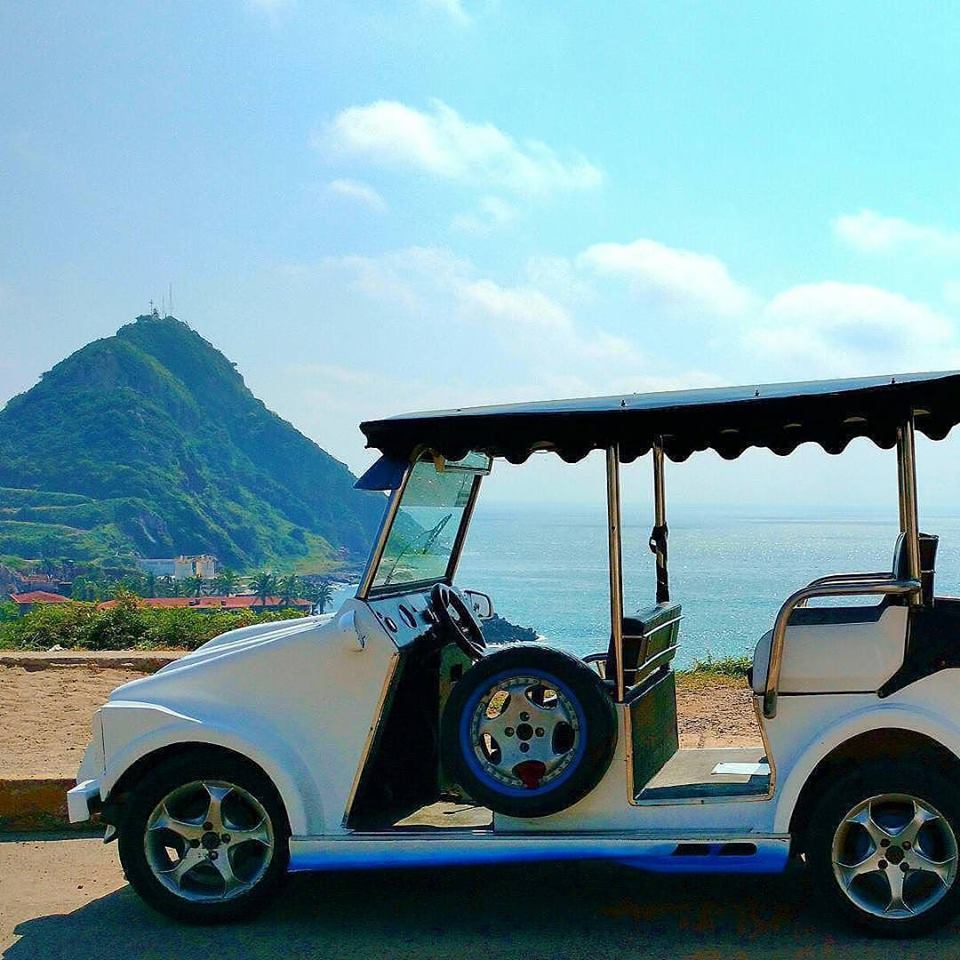 Pulmonia taxi parked along the coast with El Faro lighthouse in the far distance