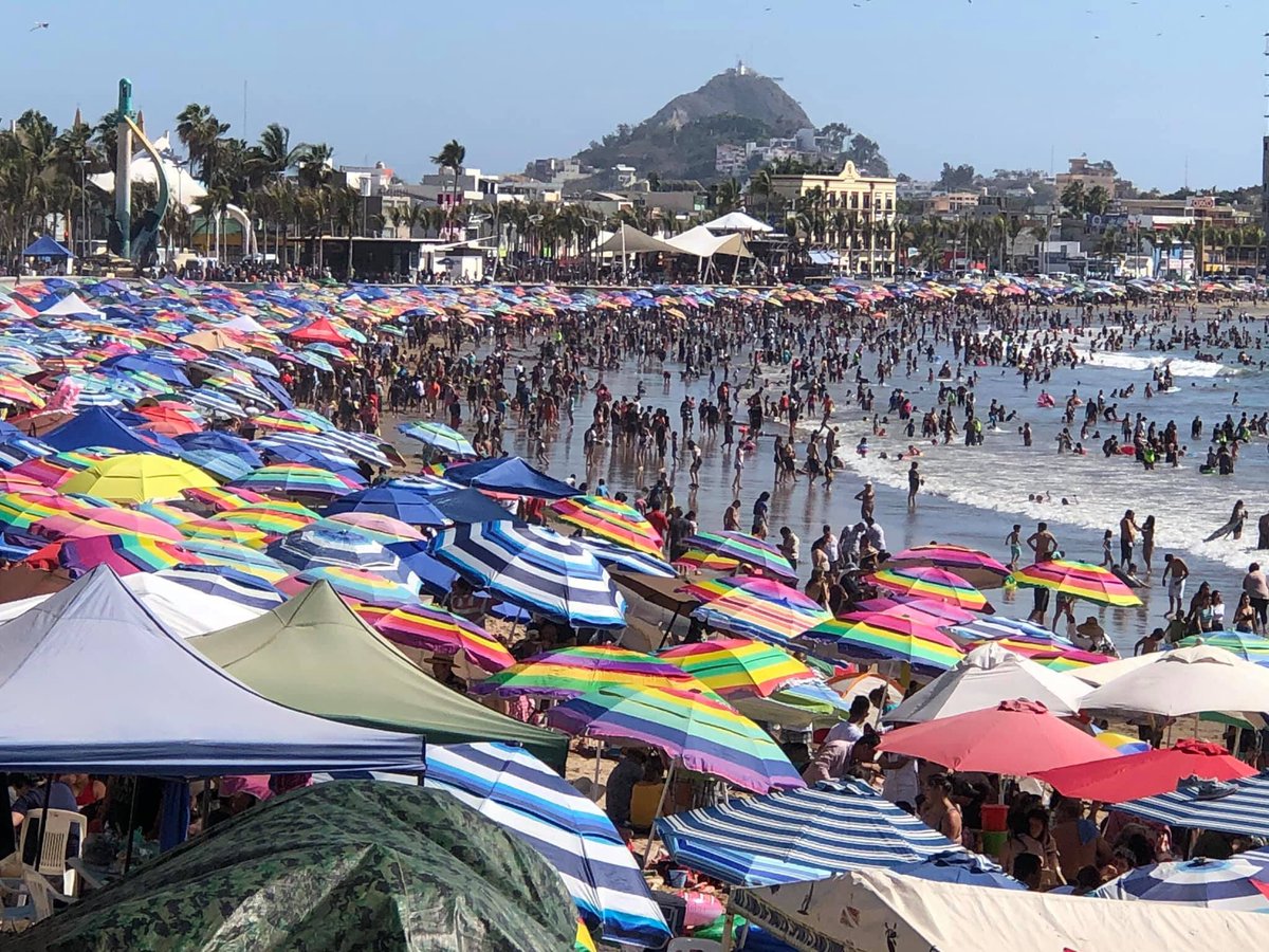 Wide ocean perspective showing the beach sands completely packed with umbrellas and vacationers