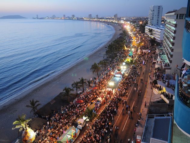 The massive Sunday Carnival parade procession crowd tracking past beachfront hotel rows