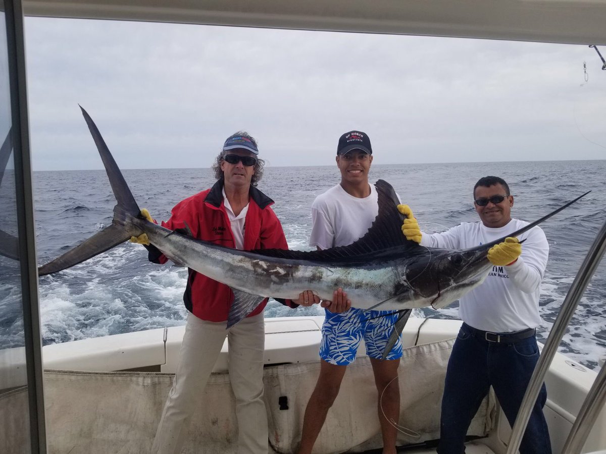 Sport fishermen showing off a massive marlin catch on the harbor docks
