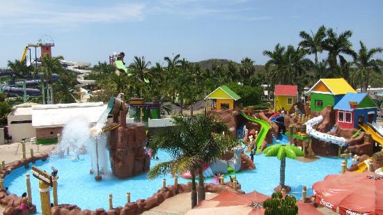 Families splashing along the primary beach entry wave pool basin at Mazagua
