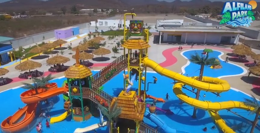 Families splashing along the main freeform swimming pools and tube slide structures at Alfiland Water Park near Mazatlán