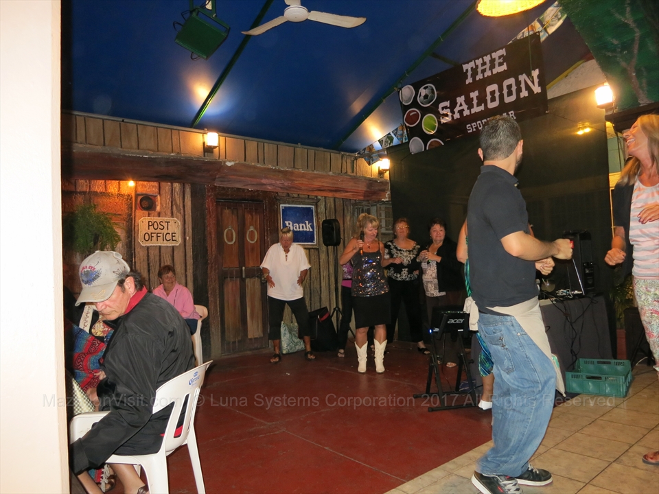 Singers taking the mic on a small stage inside a local neighborhood saloon bar